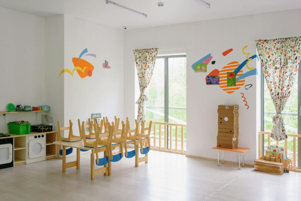 Bright and inviting kindergarten classroom with wooden chairs and playful wall art.