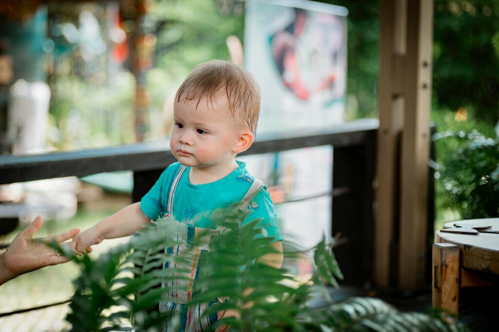 Cute toddler enjoys outdoor adventure surrounded by green plants.