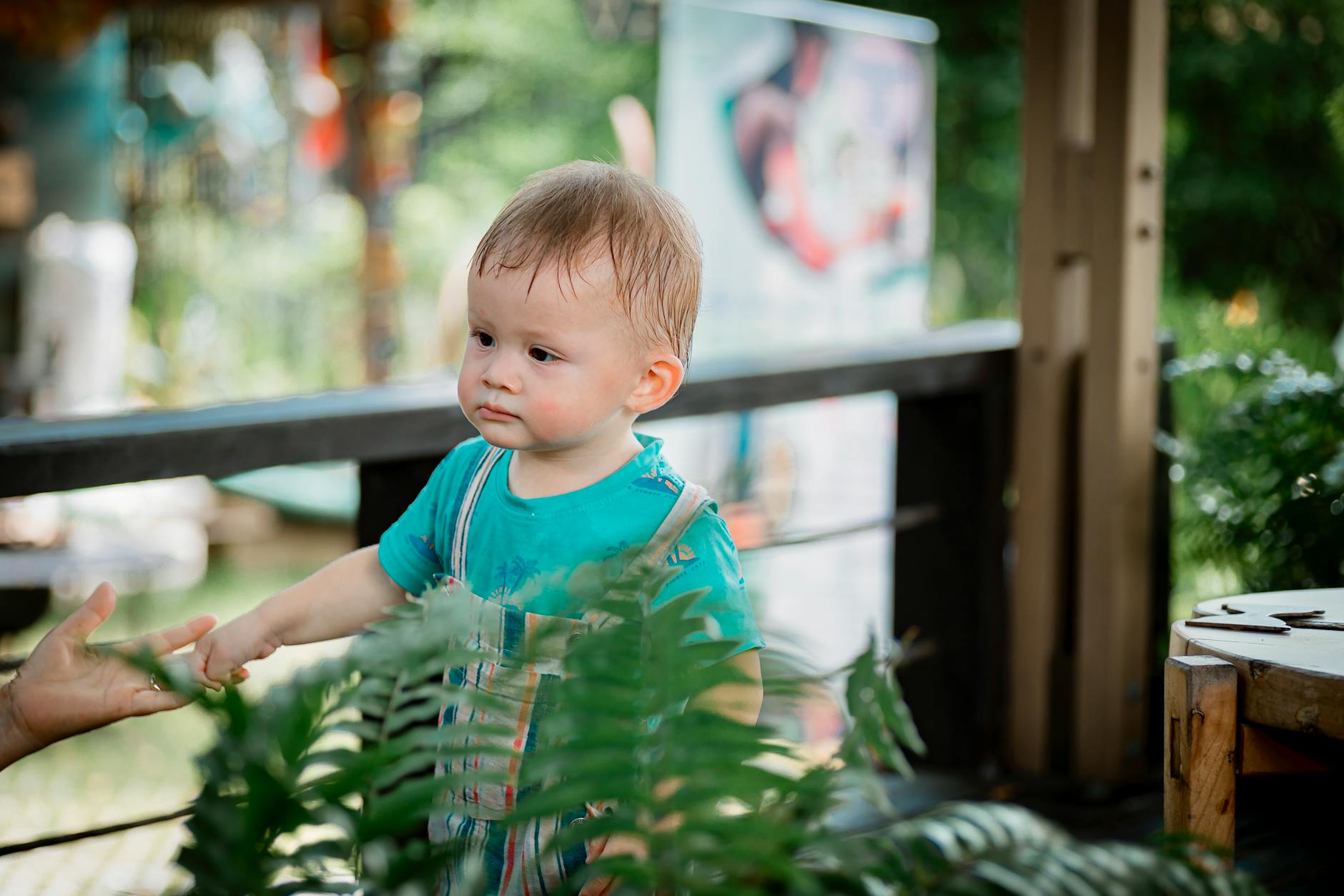 Cute toddler enjoys outdoor adventure surrounded by green plants.