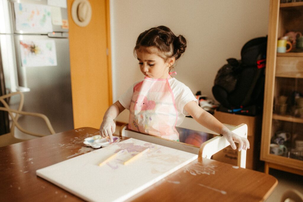 A young child passionately painting indoors, showcasing creativity and concentration.