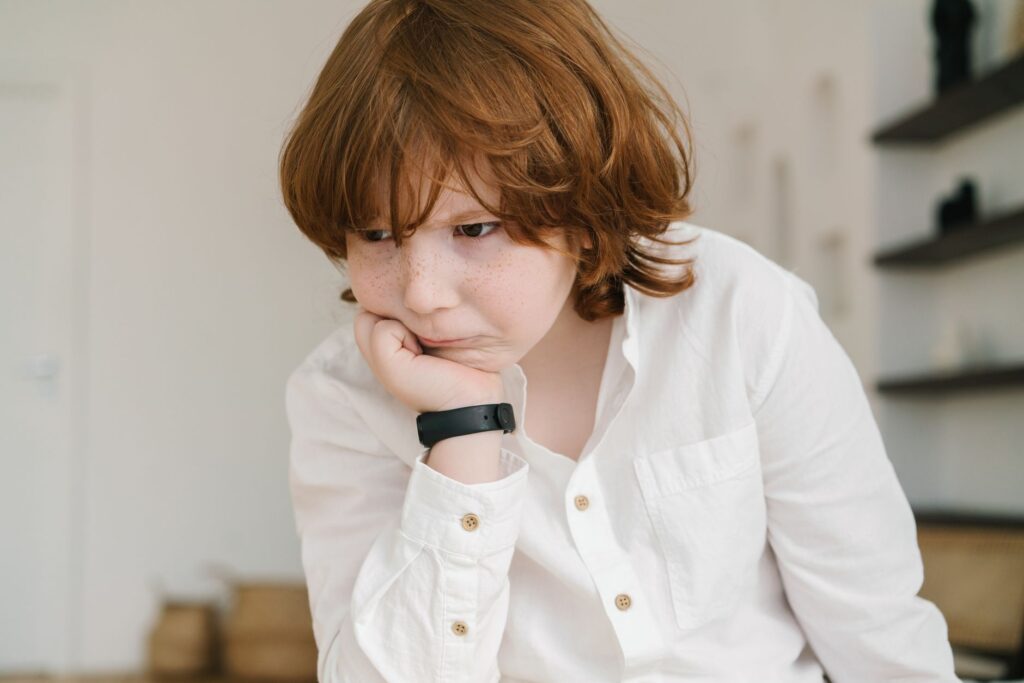 A young boy with freckles in deep concentration, wearing a white shirt.
