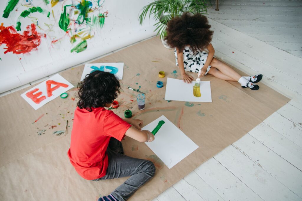 Two children painting together indoors, expressing creativity and joy through art.