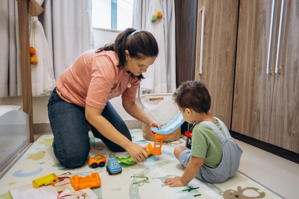 A mother and son enjoy playtime with toy cars on a room floor, creating bonding memories.