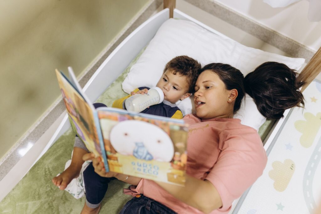 A mother reads to her young son in bed, creating a bonding bedtime routine.