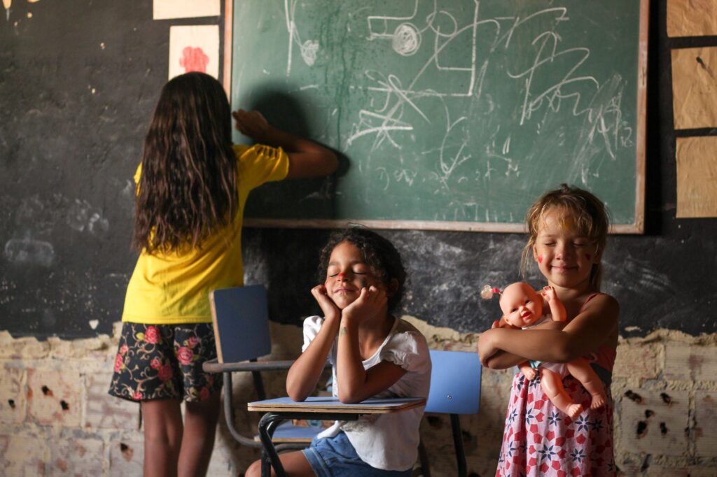 Three children in a classroom play and learn at a chalkboard in Bezerros, Brazil.