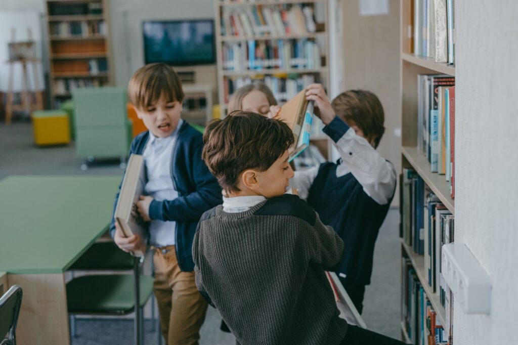 Children engaging in a playful conflict in a school library setting.