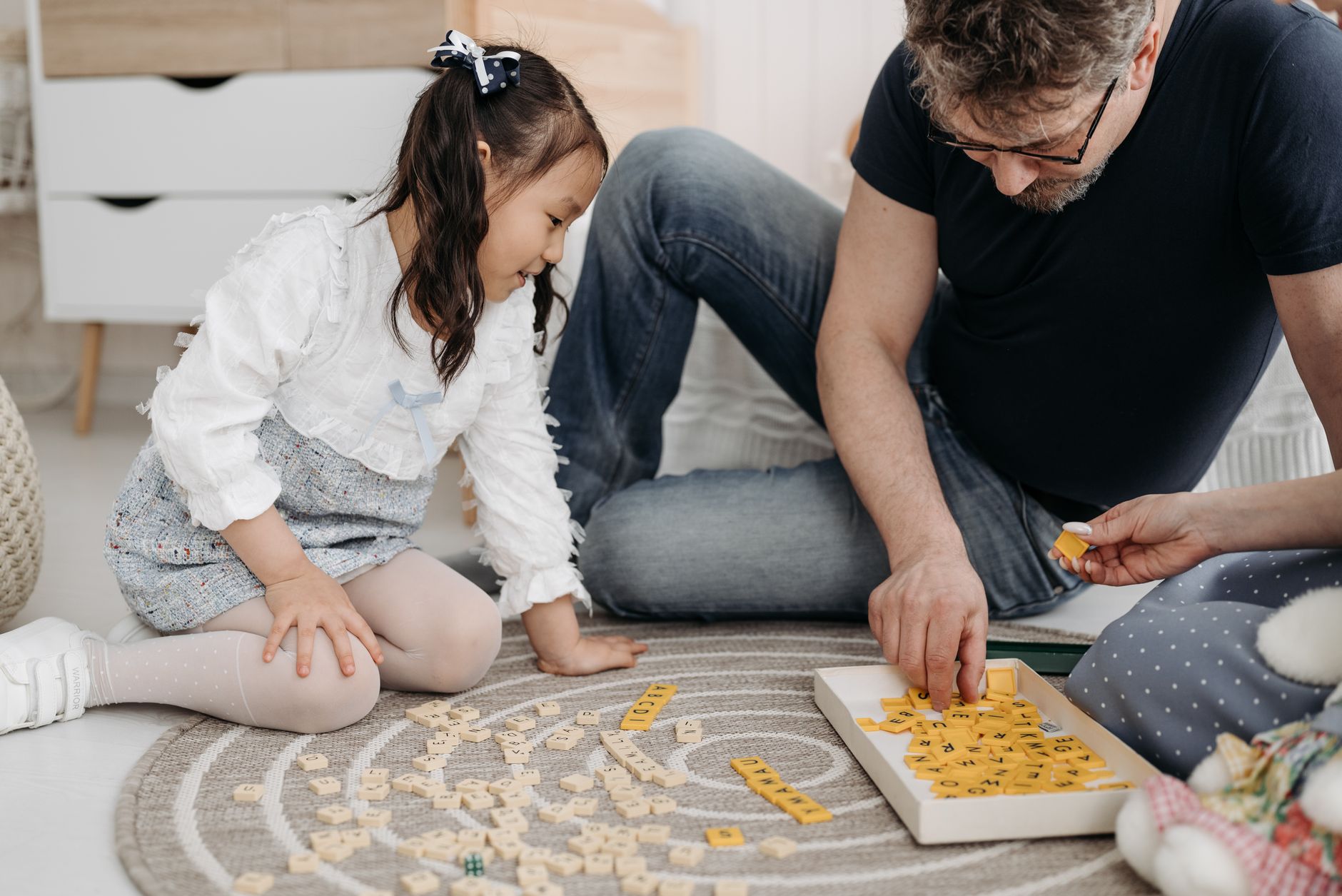 Man and girl enjoy a playful educational game together on the carpet.