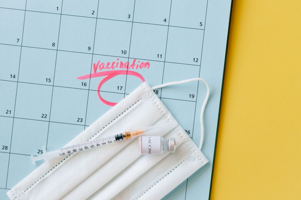 Close-up of a calendar marked for vaccination, with a syringe and face mask highlighting healthcare theme.