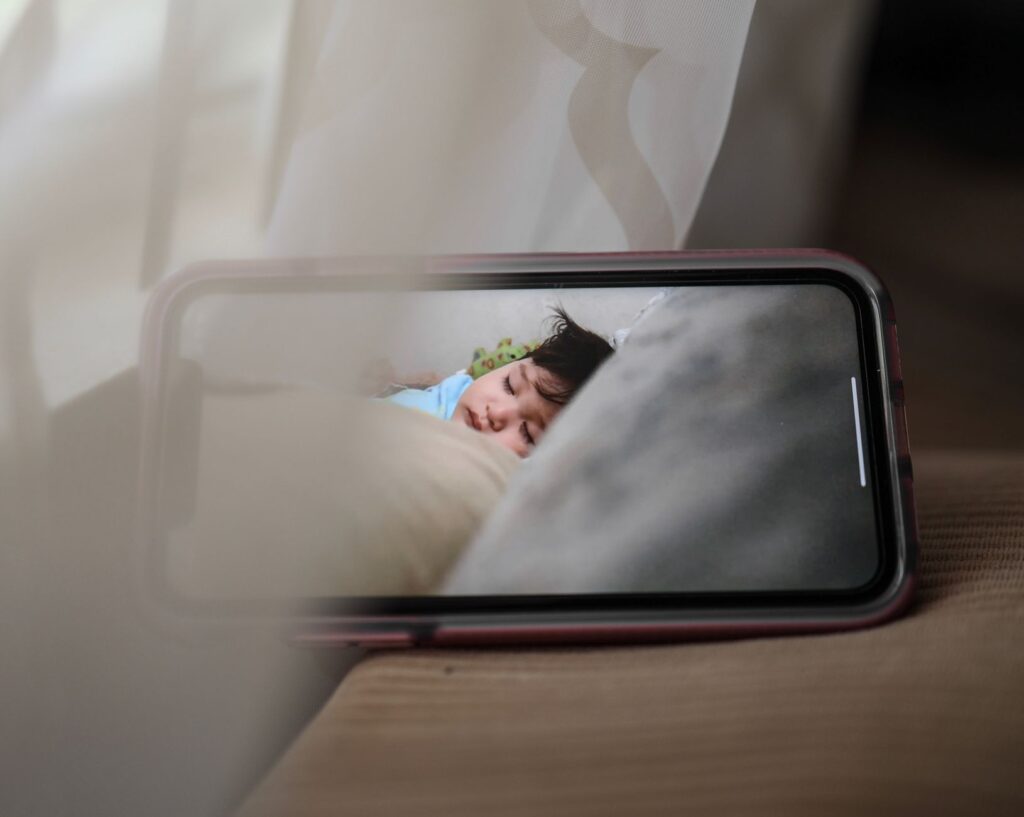 Broadcast with baby monitor of kid sleeping in crib at daytime on smartphone screen