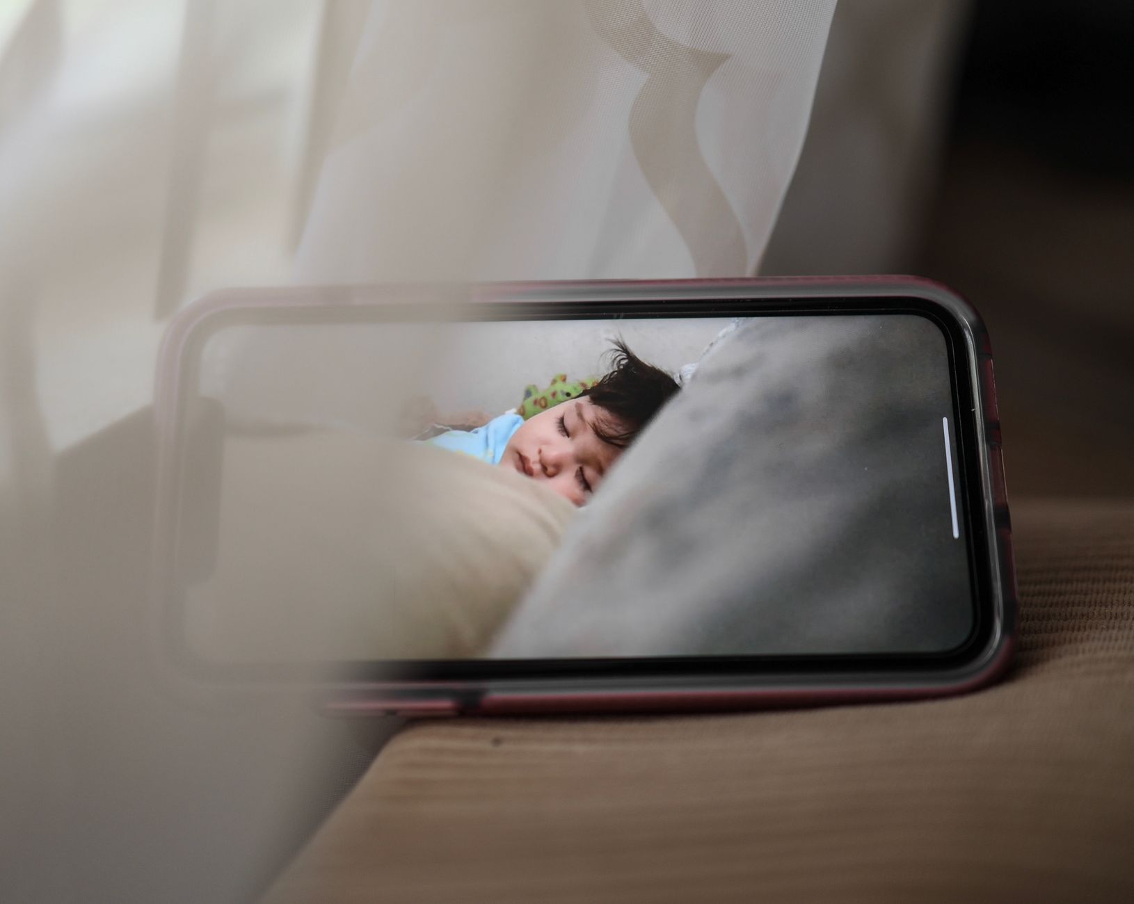 Broadcast with baby monitor of kid sleeping in crib at daytime on smartphone screen