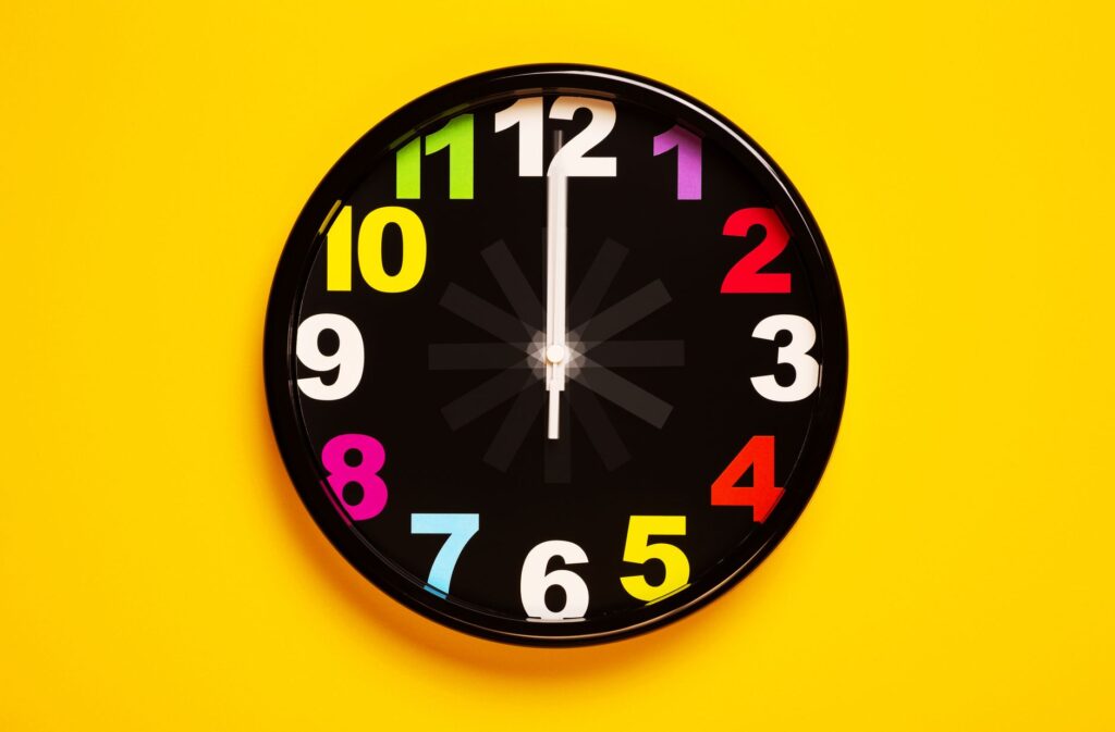 Vibrant wall clock with colorful numbers on a bright yellow background, emphasizing modern decor.