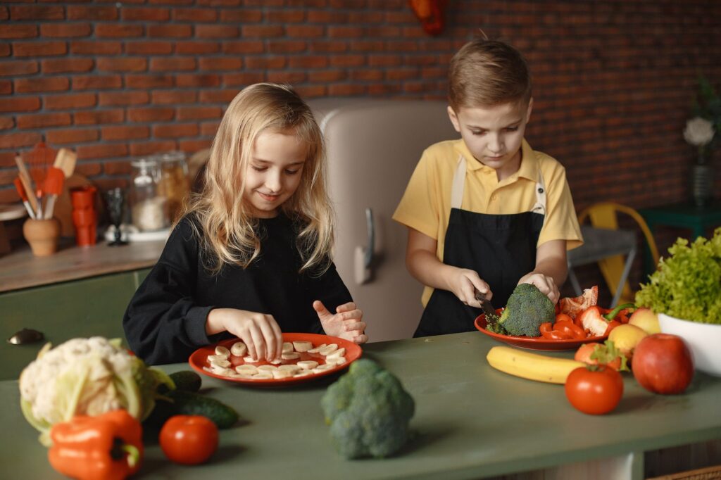 Two kids having fun preparing a healthy meal with fresh ingredients indoors.