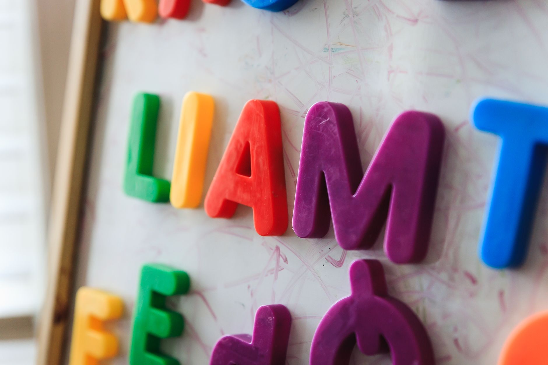 Close-up of vibrant magnetic letters spelling 'LIAM' on a whiteboard for educational purposes.