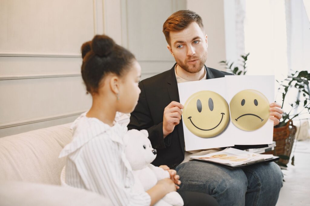 A therapist uses emotion cards to help a child express feelings during a counseling session.