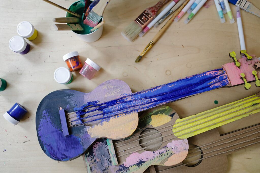 Colorful cardboard guitars with paints and brushes, showcasing artistic creativity.