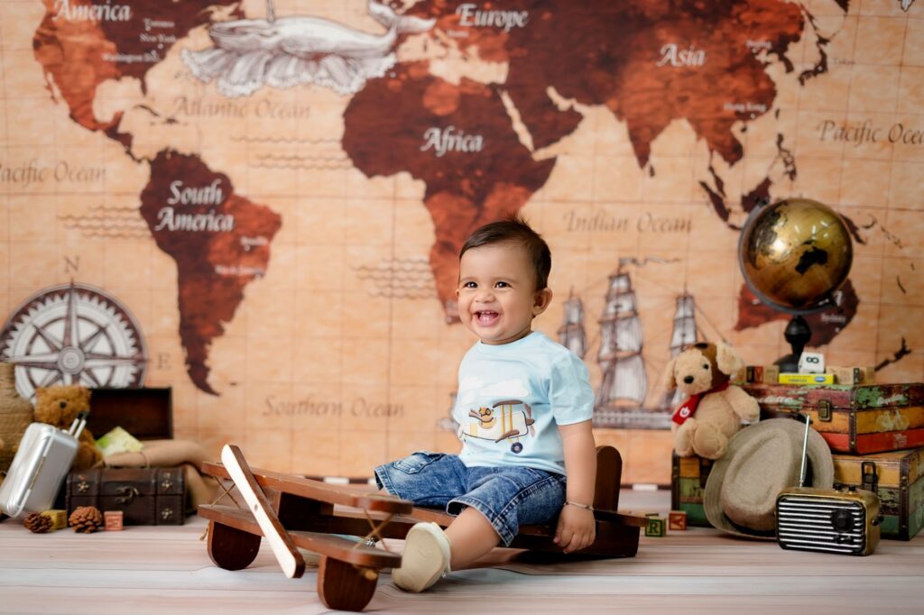 Smiling baby in a travel-themed room with globe, map, and toy plane.