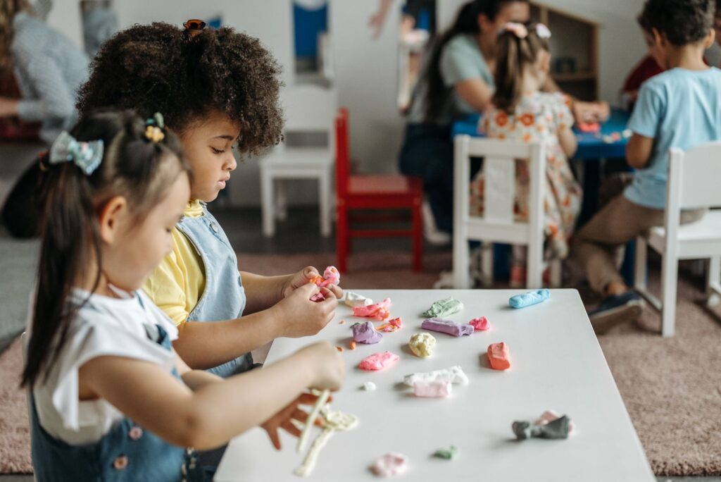 Kids at a preschool table playing with colorful clay, fostering creativity and teamwork.