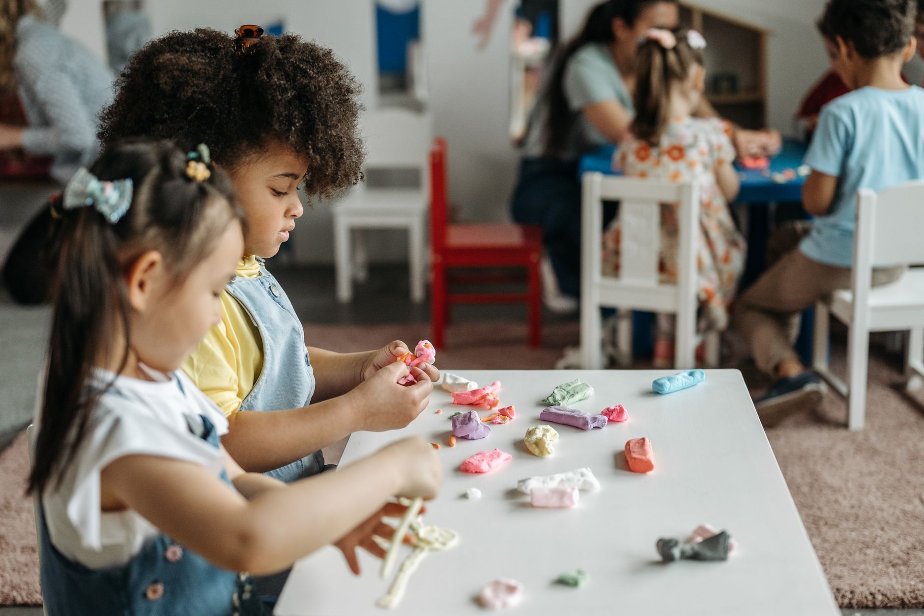 Kids at a preschool table playing with colorful clay, fostering creativity and teamwork.